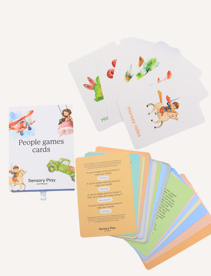 Two sets of "People Games Cards Set" by Sensory Play Australia are displayed. One set is opened, showing fanned-out cards such as "Horsey Rides" featuring a child on a rocking horse, ideal for interaction and communication enhancement. The other set is sealed.