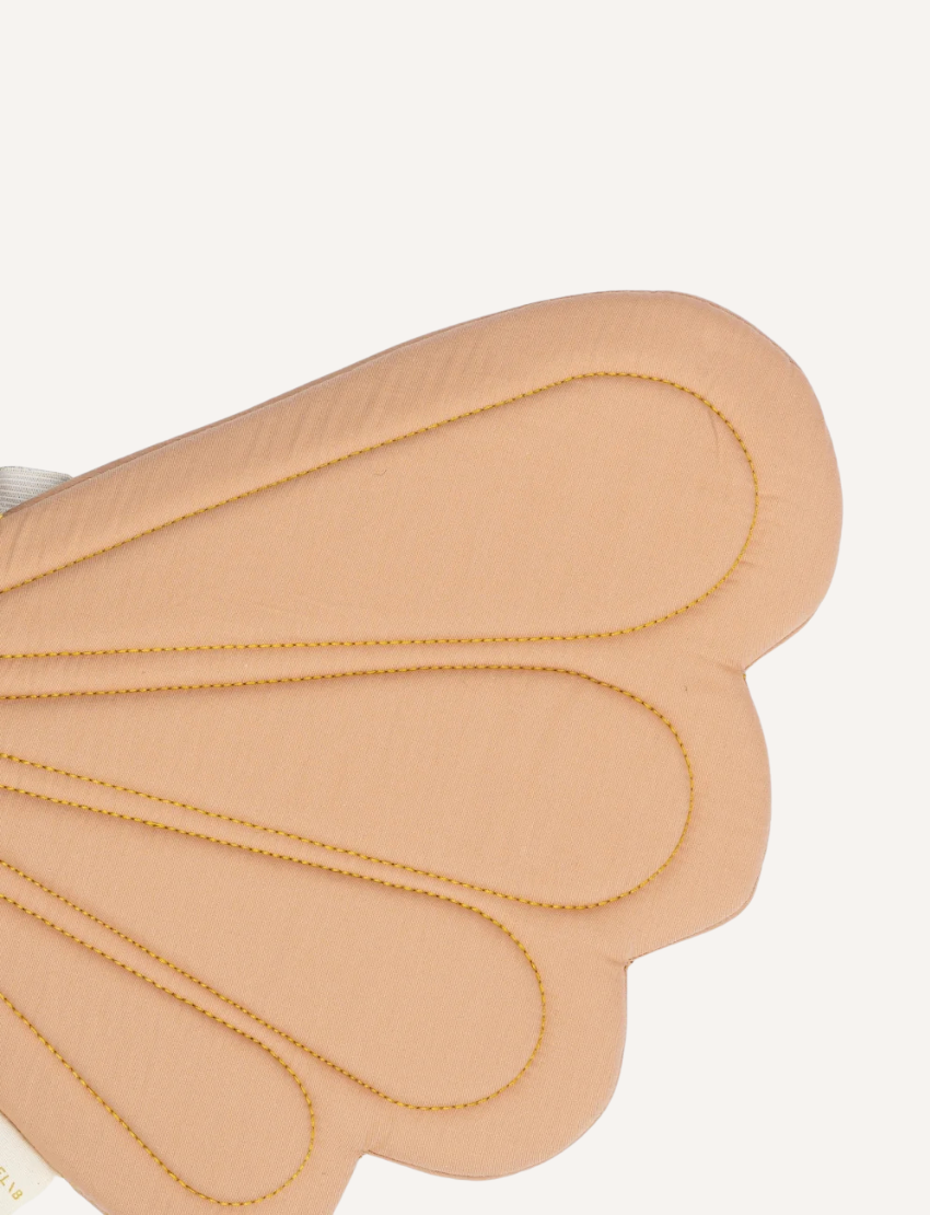 The Fairy Wings - Old Rose by Fabelab are a pair of fairy-inspired fabric wings crafted from organic cotton. These light brown wings feature scalloped edges and are secured with gold straps.