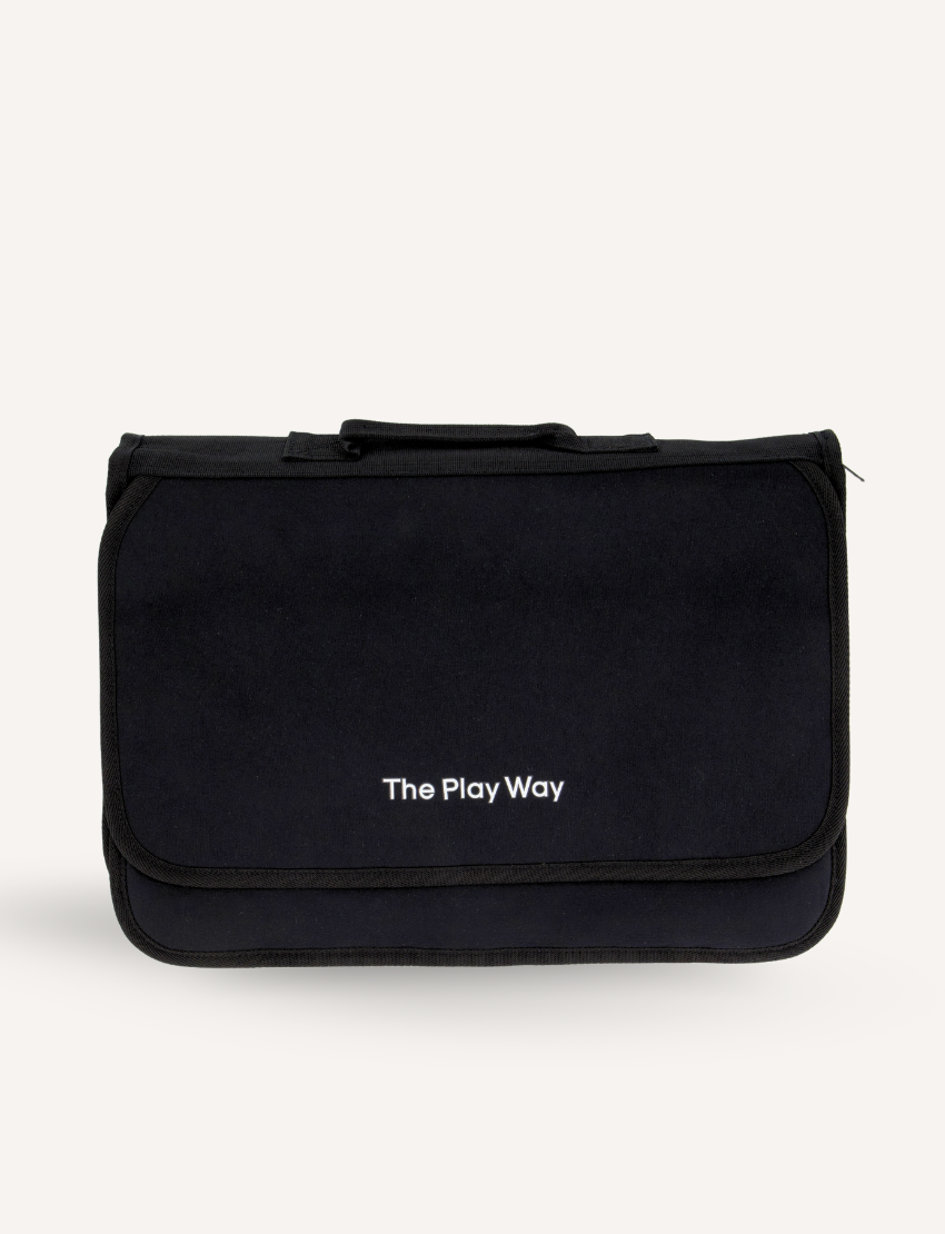 Introducing the Compendium by The Play Way: a sleek, black rectangular carrying case featuring a top handle and "The Play Way" elegantly printed in white on the front flap. Perfect as a handwriting companion, this bag keeps your writing tools organized and easily accessible against its pristine white background.