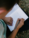 The Time in Nature Handwriting Kit by The Play Way is a teal cardboard box filled with items for outdoor exploration. Visible contents include a pair of binoculars, a magnifying glass, nature activity cards, a spool of twine, and two small booklets titled 