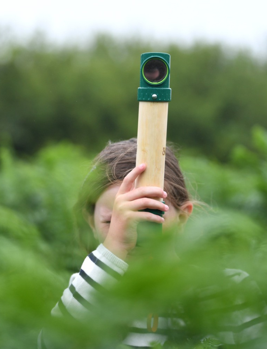 The Hape Hide-and-Seek Periscope features a bamboo and green plastic design, complete with an orange wrist strap, standing vertically against a plain background.