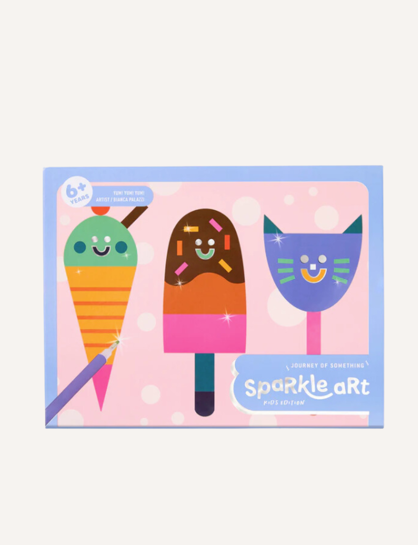 A brightly colored box labeled "Kids Sparkle Art - Yum! Yum! Yum!" features illustrations of a carrot, a popsicle, and a cat, each with smiling faces. The packaging indicates it's suitable for ages 6 and up and is part of the Journey of Something kids' edition.