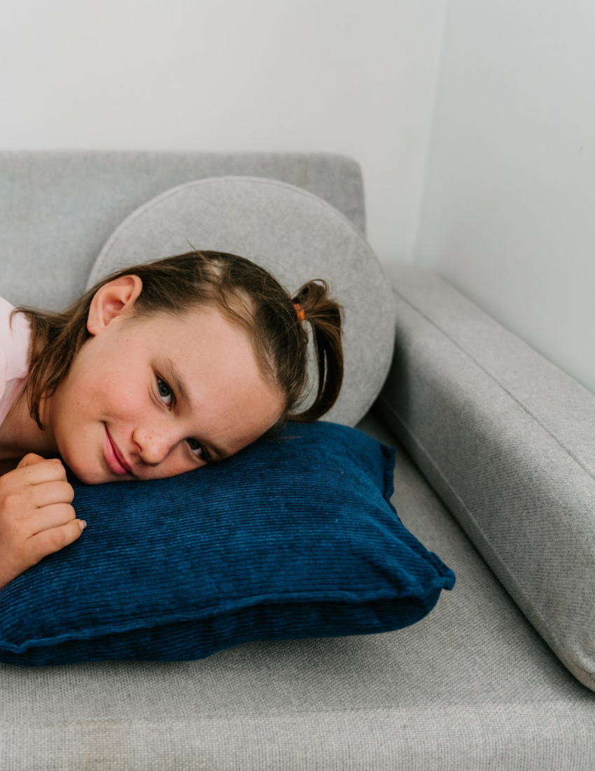 A Sensory Play Australia Vibrating Cushion, adorned in dark blue with a plain design, rests on a light-colored flat surface. The cushion features slightly rounded corners and includes a small fabric tag on one side.