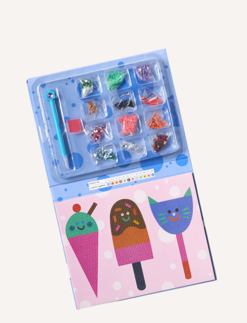 A brightly colored box labeled "Kids Sparkle Art - Yum! Yum! Yum!" features illustrations of a carrot, a popsicle, and a cat, each with smiling faces. The packaging indicates it's suitable for ages 6 and up and is part of the Journey of Something kids' edition.