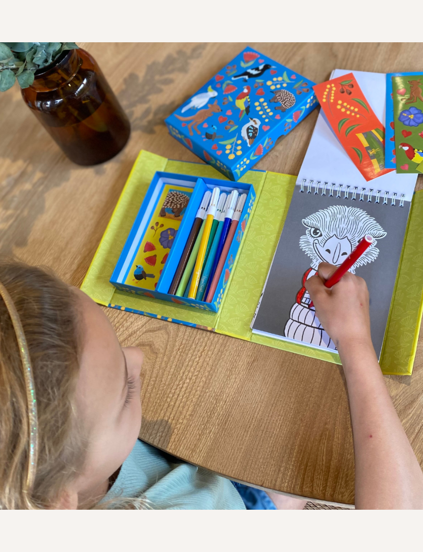 Four Colouring Set boxes from Tiger Tribe are on display, ideal for entertaining activities for children. Each set showcases a unique theme: zoo animals, rainforest animals, dinosaurs, and forest fairies. The boxes are adorned with vibrant illustrations reflecting their respective themes and include a warning label.