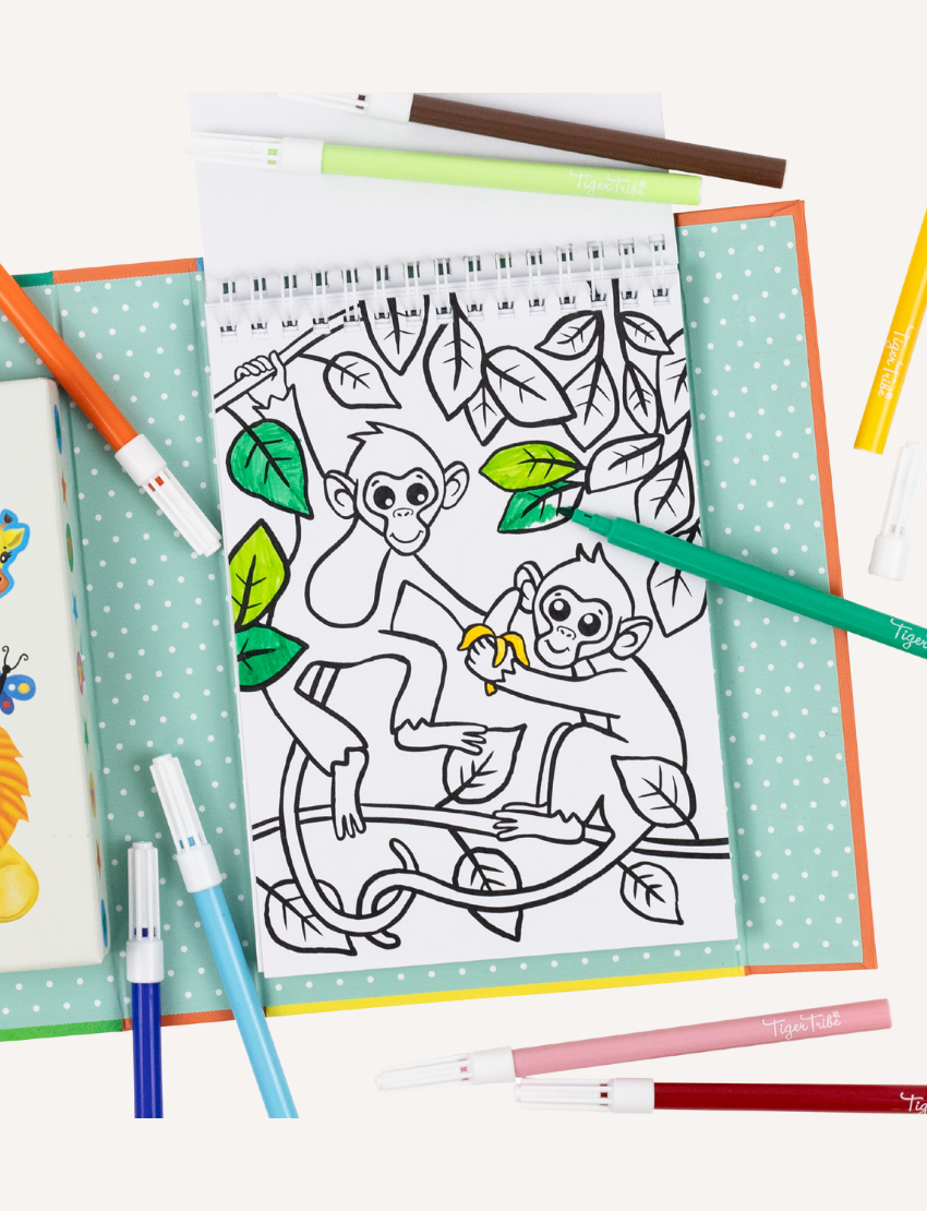 Four Colouring Set boxes from Tiger Tribe are on display, ideal for entertaining activities for children. Each set showcases a unique theme: zoo animals, rainforest animals, dinosaurs, and forest fairies. The boxes are adorned with vibrant illustrations reflecting their respective themes and include a warning label.