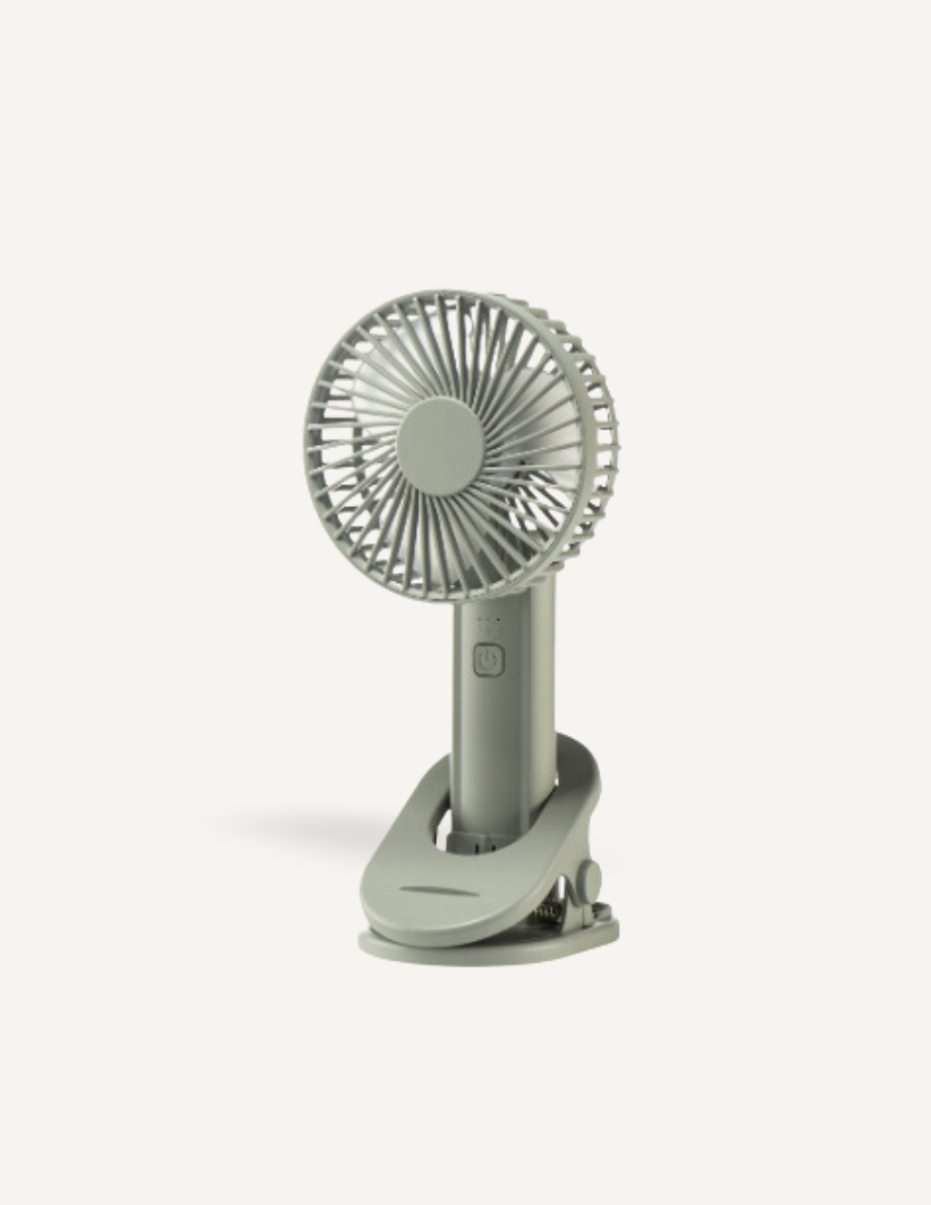 A small, gray, Sensory Play Australia Sleep Fan with a circular blade guard and a clip base stands upright on a white background. This portable fan produces gentle white noise and features a power button on the front, making it perfect for creating a calming atmosphere.