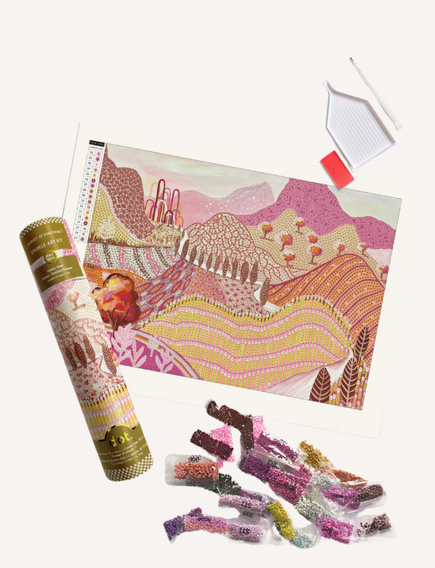 The Sparkle Art Kit by Journey of Something features a vibrant landscape of pink and purple hills and trees. It includes a printed canvas, sparkle dots, colored bead packets, a white tray, and a pen tool, making it perfect for unleashing your creativity.