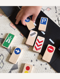 Introducing the Road Blocks Set Traffic Signs by Waytoplay, a charming collection of wooden toy blocks featuring traffic symbols. This set includes a block with a pedestrian sign, another showcasing a traffic light, and a third adorned with red and white arrows. The blocks can be displayed both upright and lying flat for versatile play.