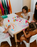 A large green box contains children's art supplies designed to foster creative expression: it features the Jar Melo Fine Motor Practice: Puzzle and Art Kit, which includes a pack of Giant Finger Paint Paper with a blue octopus and yellow crocodile, a Dot Painting Kit filled with colorful dots, and animal-themed tools that enhance fine motor skills.