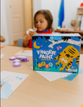 The Play Way's Fine-Motor Practice: Puzzle and Craft Kit is a large open green box designed to enhance sensory-rich creativity and early learning. It includes a variety of children's art supplies such as a coloring book, a finger paint set, colored shapes, markers, and activity cards, all showcased against a plain white background.