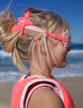 On a plain background, two pairs of Sunnylife's Mini Swim Goggles are displayed. The top pair is pink adorned with a shell design, while the bottom pair is blue with intricate shark details, including fins and teeth.