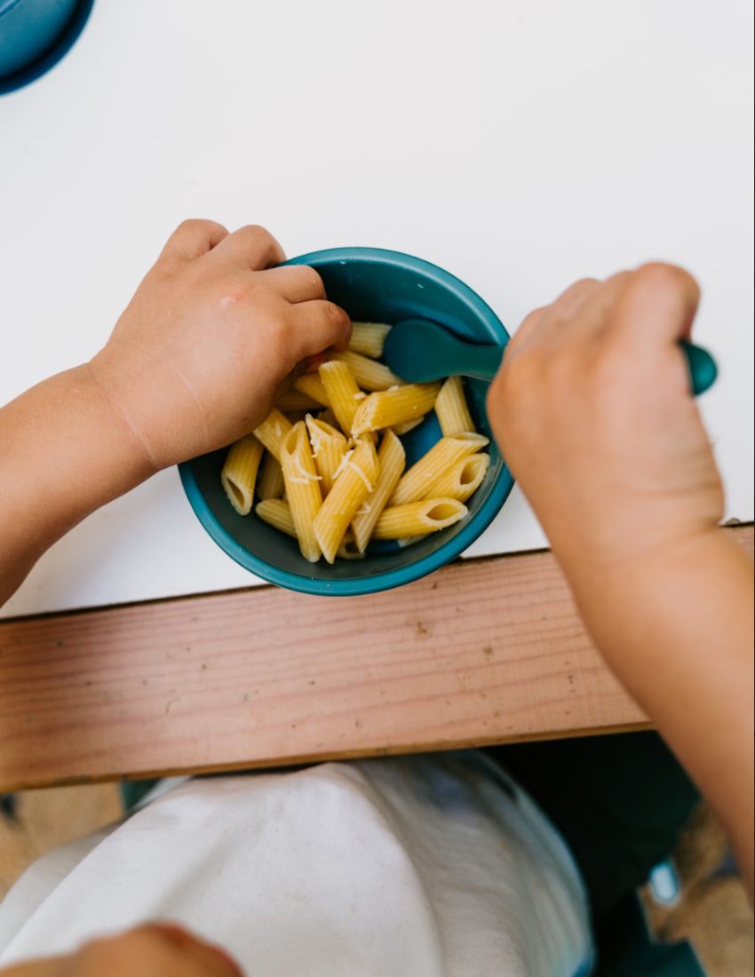 The Sensory Friendly Food Handling Kit by The Play Way comes in a cardboard box containing an assortment of kitchen utensils, ideal for enhancing fine motor skills. It includes peelers, fruit sticks, and a versatile kitchen tool, all neatly displayed in open brown boxes with a green and blue patterned box beneath.