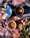 The Sensory Friendly Food Handling Kit by The Play Way comes in a cardboard box containing an assortment of kitchen utensils, ideal for enhancing fine motor skills. It includes peelers, fruit sticks, and a versatile kitchen tool, all neatly displayed in open brown boxes with a green and blue patterned box beneath.