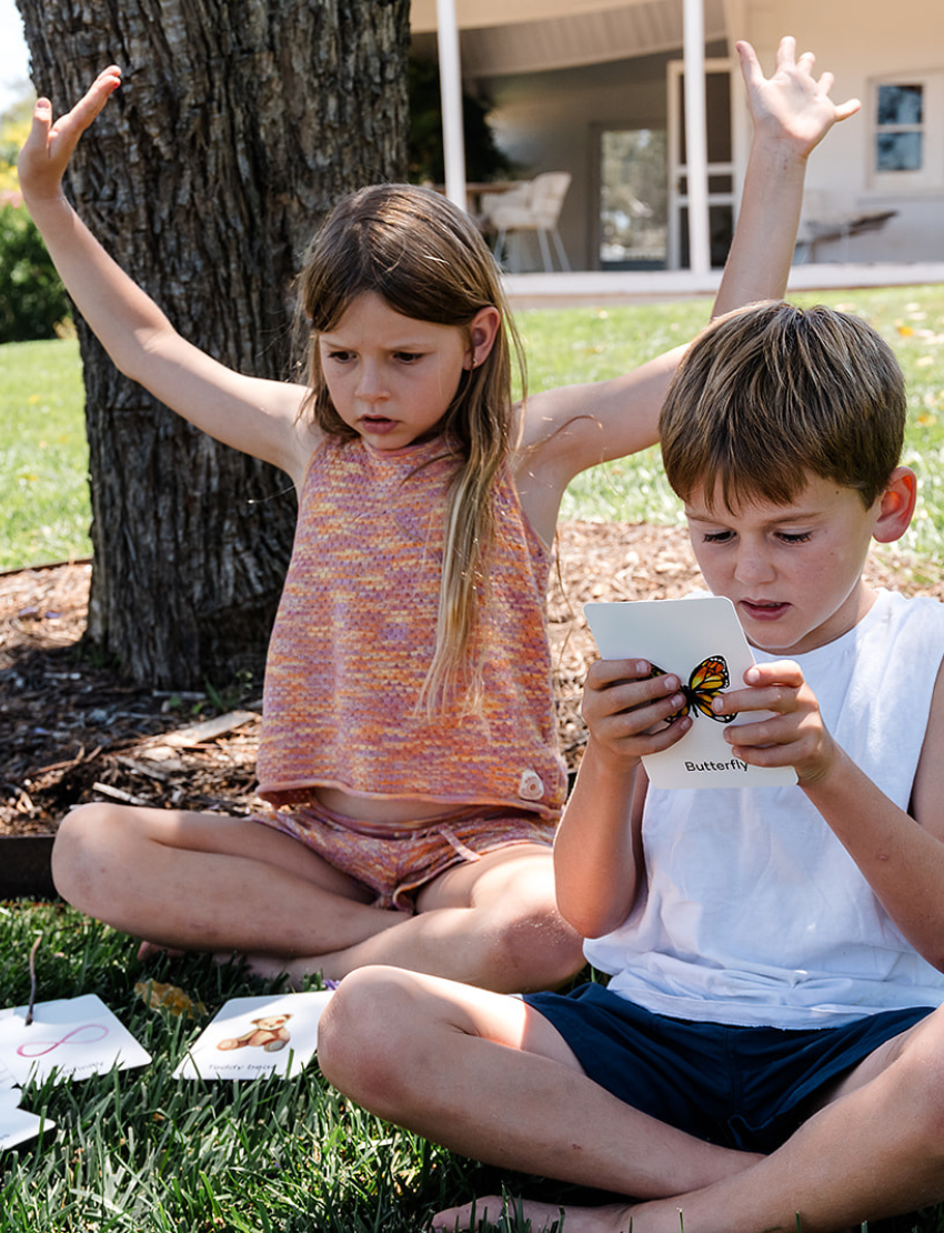 The Regulation and Reflection Kit by The Play Way contains various educational and sensory items. Visible items include a book titled "STIMS, SCHOOL & ME," breathing cards, a mini MP3 player, reflective journal cards, a sensory play kit, and a book titled "The Buzzing Busy Brain.