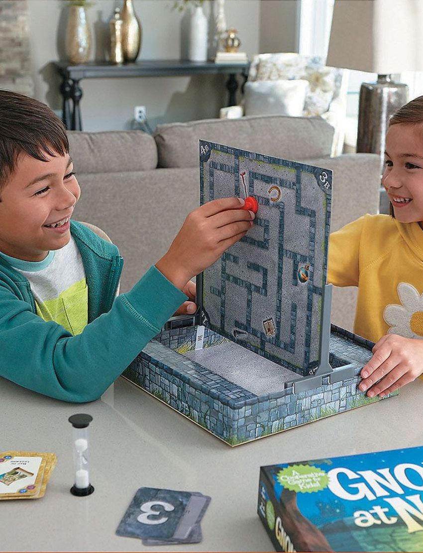 The image shows the box for the Gnomes at Night Game by Peaceable Kingdom, featuring two gnomes with lanterns in front of a stone maze, set against trees and a night sky.