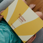 Lifestyle image of a child holding the yellow box of the Routines Buddy Magnetic Planner Set on their lap. A toolkit from Sensory Play Australia designed to empower children and families with daily routines.