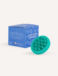 A turquoise Melo Hair Care Kit scalp therapy massager by The Play Way, featuring a round design and soft bristles, is pictured next to its blue box packaging. The box includes text instructions and caution warnings. The background is white.