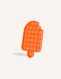 The Preppit Pop It is an orange, ice-cream shaped sensory toy featuring evenly spaced bubble-like buttons. Designed with a small bite-shaped notch at the top left corner and a flat bottom with a short stick-like handle, this toy is ideal for sensory regulation or as a distraction during mealtime. The background is plain white.