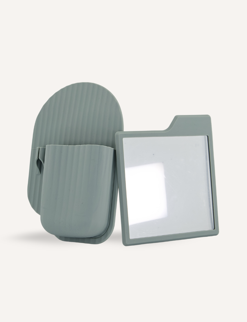 The Bathroom Organiser and Shower Mirror Set by Sensory Play Australia includes a green, rectangular magnifying glass with a fold-out stand that's perfect for aiding self-care routines. The stand features a curved, ribbed texture and folds into a compact, portable size, making it an ideal addition to your bathroom organiser.