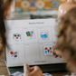 A child's hand places a "Family time" picture icon onto a magnetic Weekly Planner. This visual aid helps children understand their schedule with icons for school and sports, reducing anxiety by building a clear routine.