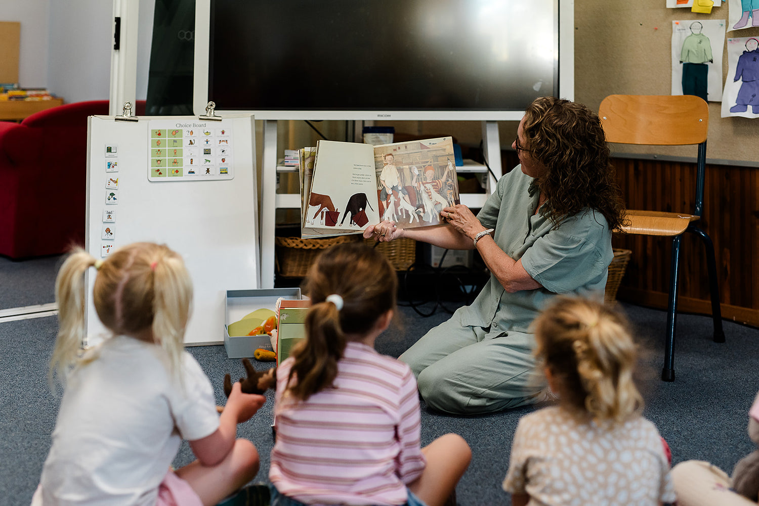 Teacher reading a book to young children sitting on the floor in a classroom.