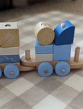 The Moover Block Train features four carriages with colorful block animals—a cartoon fox, raccoon, bunny, bear, and bird. Made with non-toxic paints on a natural wooden base with wheels, it's perfect for enhancing young children's motor skills.