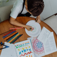 The Creative Mindfulness: Mandalas Program by The Play Way includes a vibrant open box with markers, colored pencils, notebooks, paint, a tote bag, and crafting materials. It has abstract green, purple, and orange patterns with "The Play Way" text.
