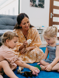 The Early Years Language Program by Therapy At Home features an open teal box neatly filled with educational toys, animal figurines, wooden blocks, a toy tea set, illustrated cards, books, and activity sheets for play-based learning and language development.