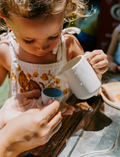 The Early Years Language Program by Therapy At Home features an open teal box neatly filled with educational toys, animal figurines, wooden blocks, a toy tea set, illustrated cards, books, and activity sheets for play-based learning and language development.