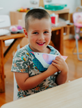 The Therapy At Home Fine Motor Advanced Program features a vibrant box with modeling clay, a 3D paper model kit, cards, stickers, markers, and more—ideal for building fine motor skills as recommended by occupational therapists.