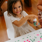 Young girl practices fine motor skills, adding dots to paper with a bottle, using The Play Way Fine Motor Foundations Program.