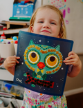 The Therapy At Home Fine Motor Intermediate Program is an open teal box with abstract designs featuring craft and activity sets to strengthen fine motor skills using reusable stickers, sand art, air-dry clay, glue, and storybooks.