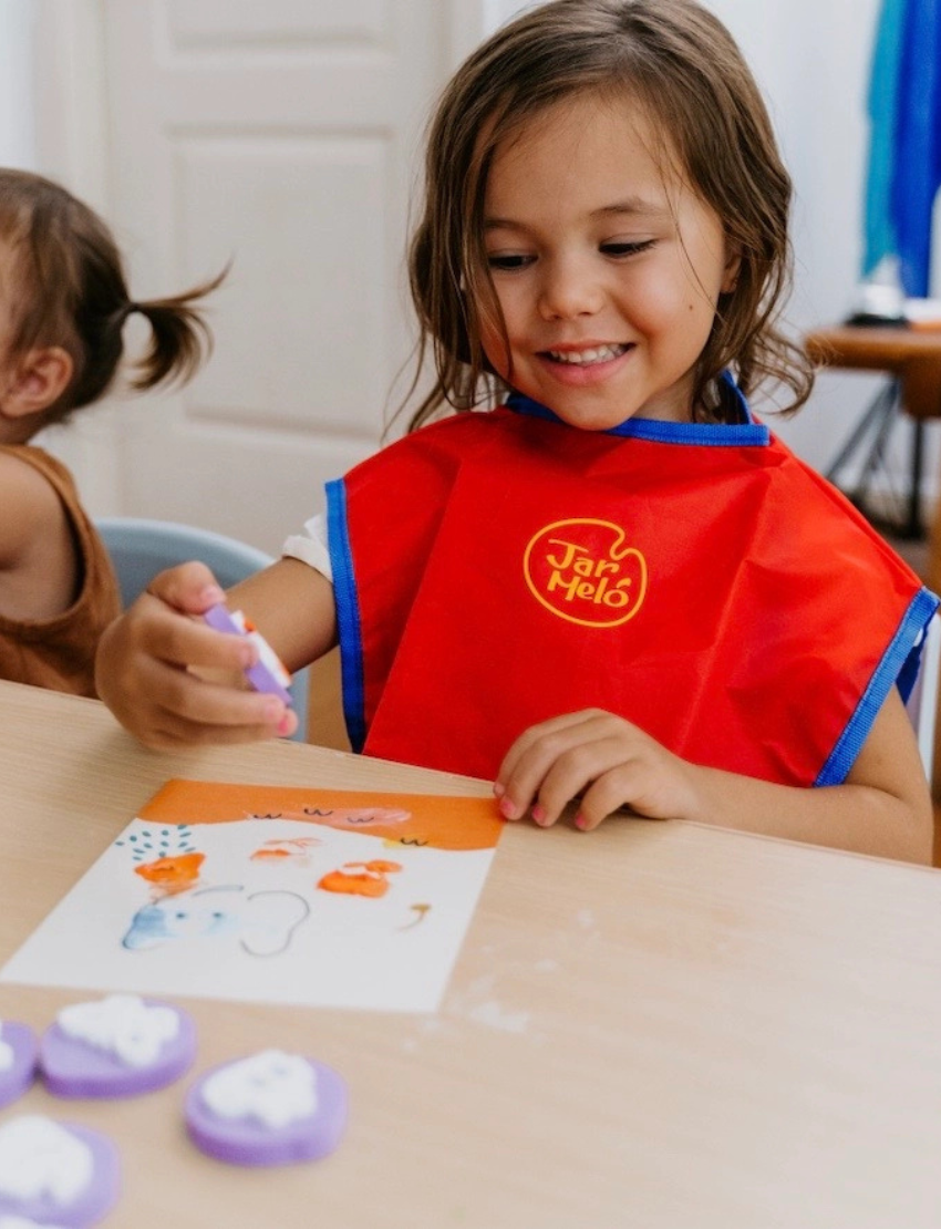 The Play Way's Fine-Motor Practice: Puzzle and Craft Kit is a large open green box designed to enhance sensory-rich creativity and early learning. It includes a variety of children's art supplies such as a coloring book, a finger paint set, colored shapes, markers, and activity cards, all showcased against a plain white background.