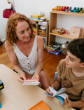 An open Therapy At Home Language Promotion Program box with playful green and teal designs reveals educational books, cards, and colorful language development activity materials neatly arranged inside.