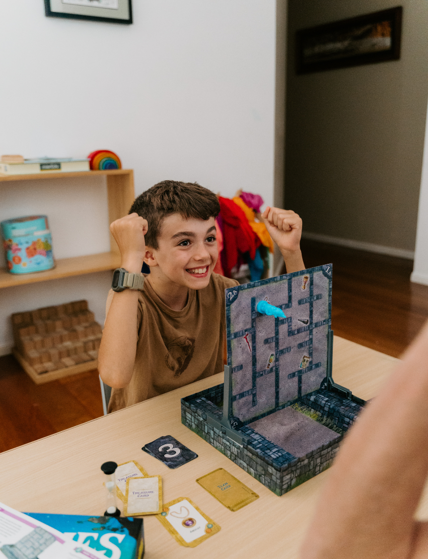 A teal box from The Play Way, called the Language Promotion Program, offers educational materials and board games like "Gnomes at Night," "Link it Up," and "Make 'N' Break." It includes a flyer on a language arts unit to boost language skills with fun activities.