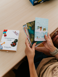 An open Therapy At Home Language Promotion Program box with playful green and teal designs reveals educational books, cards, and colorful language development activity materials neatly arranged inside.