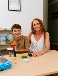 An open Therapy At Home Language Promotion Program box with playful green and teal designs reveals educational books, cards, and colorful language development activity materials neatly arranged inside.