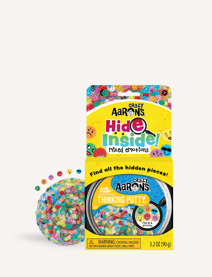 The image displays the packaging for Crazy Aarons Mixed Emotions Hide Inside Putty. It features a tin of putty, a checklist of hidden objects, and various play suggestions on the back. The packaging is vibrant with yellow and blue accents.