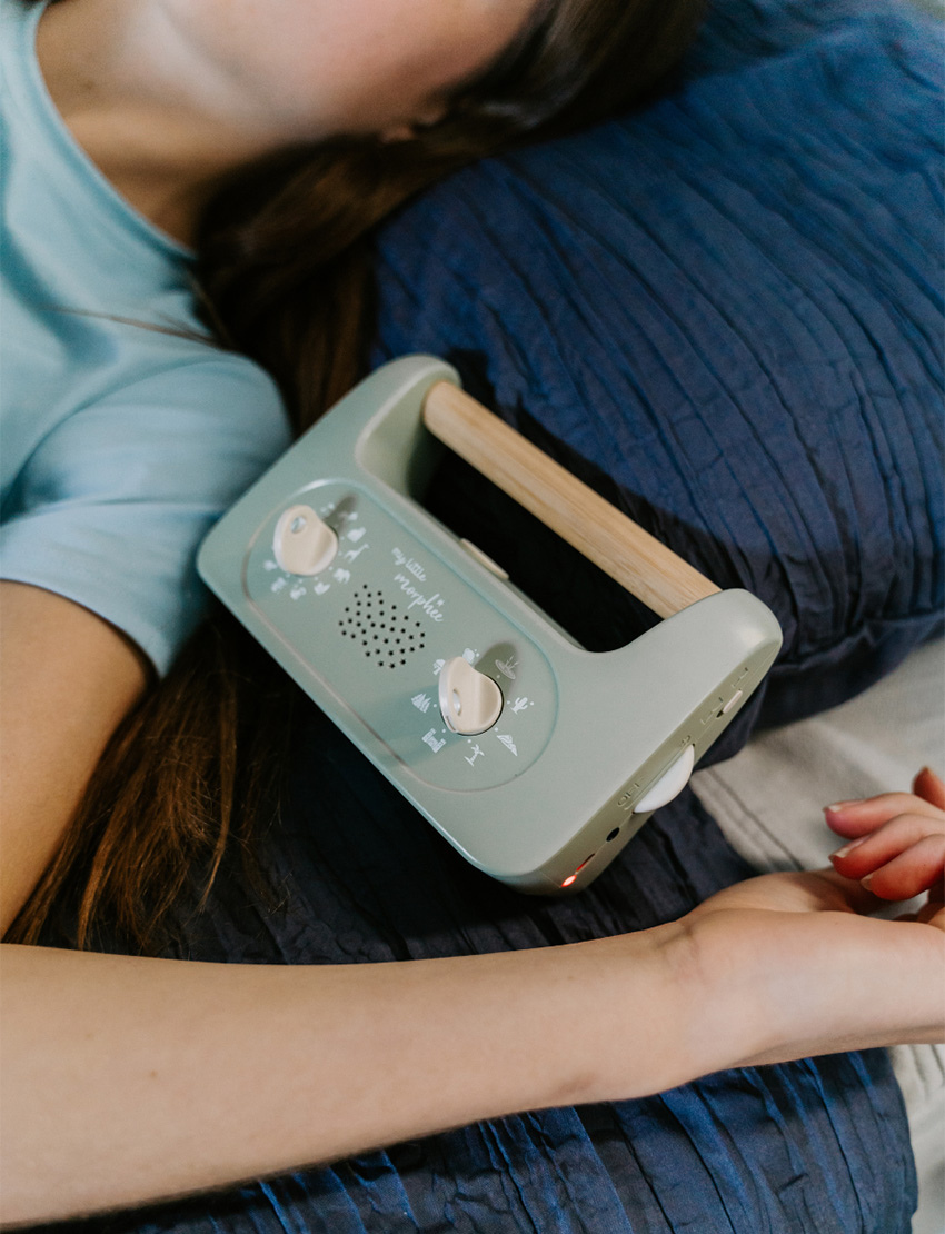 Sporting a soft green design and a wooden handle, the My Little Morphee Relaxation & Sleep Aid by Morphee features two dials and a speaker grille. The front showcases white illustrations along with the brand name "my little morphée," providing calming sounds for restful sleep.