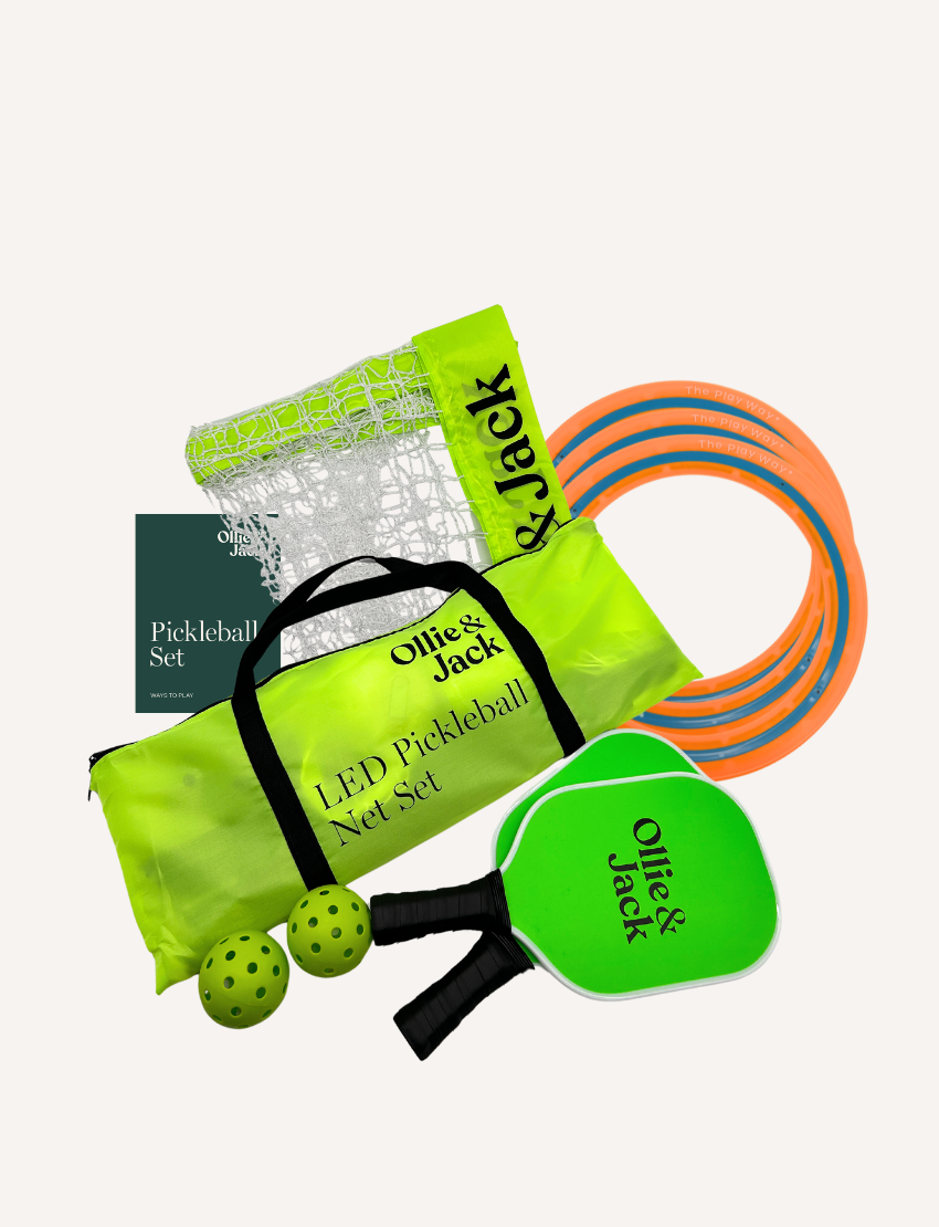 The Play Way's Outdoor Action Bundle offers pickleball excitement with a green bag, two "Ollie & Jack" paddles, a rolled LED net, two green holed balls, orange boundary markers, and an instruction booklet.