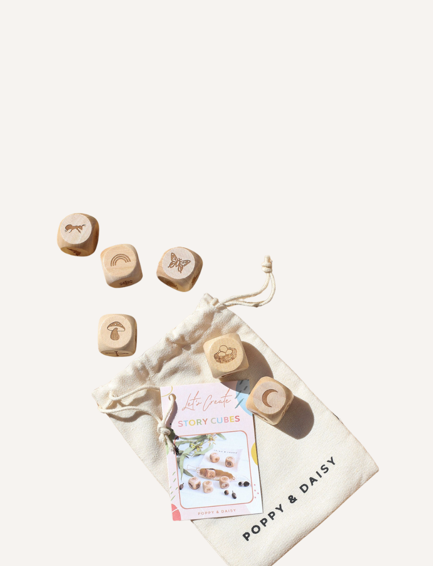 A "Poppy & Daisy" drawstring bag is open, showcasing Nature Story Cubes and an instruction booklet. Each wooden cube features a unique engraved image, such as a bee, footprint, and squirrel.