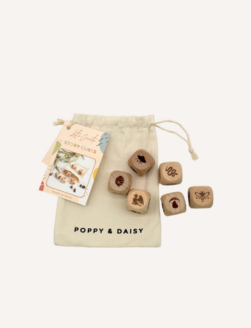 A "Poppy & Daisy" drawstring bag is open, showcasing Nature Story Cubes and an instruction booklet. Each wooden cube features a unique engraved image, such as a bee, footprint, and squirrel.