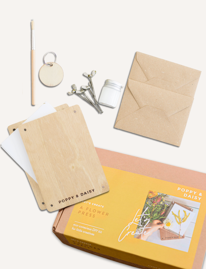 The Poppy & Daisy Flower Press kit is perfect for creating pressed flowers and includes wooden boards engraved with "Poppy & Daisy" text, a small jar, screws, a pencil, a blank round keychain as a unique keepsake, and a craft envelope. The packaging features an illustrated label with a floral pressing design.