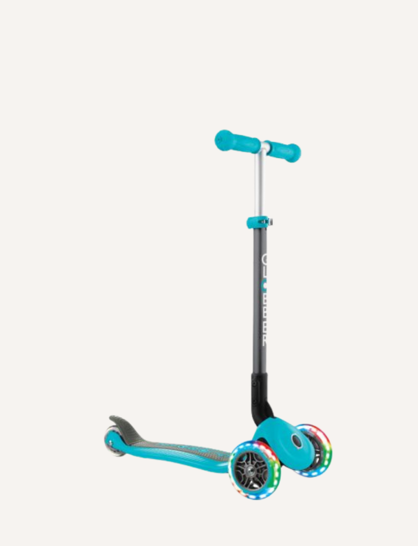 The PRIMO Foldable Lights Scooter by Globber is a blue children's scooter featuring three wheels, a T-shaped handlebar, and LED lights on the front wheels. It boasts a sleek design with a sturdy frame, casting a shadow on the ground.