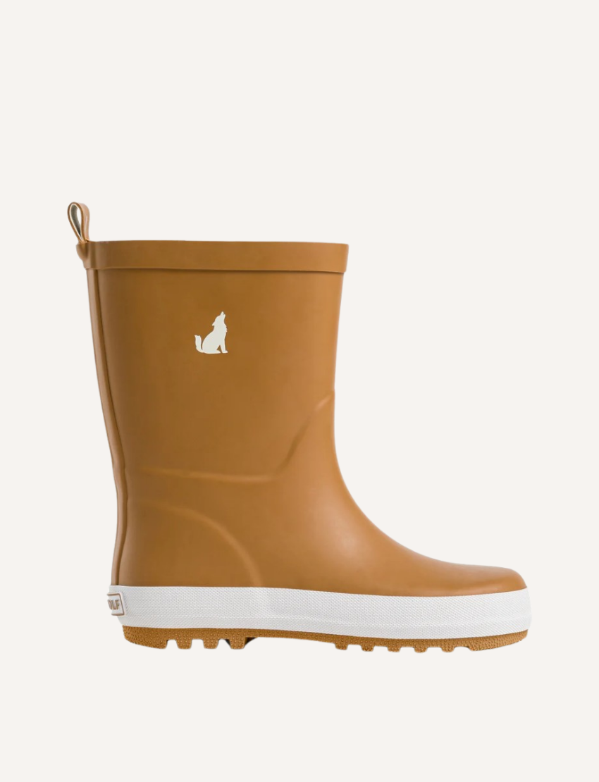 The Rain Boots - Tan by Cry Wolf feature a white sole, a small white logo of a howling wolf on the side, and a convenient pull-on loop at the back.