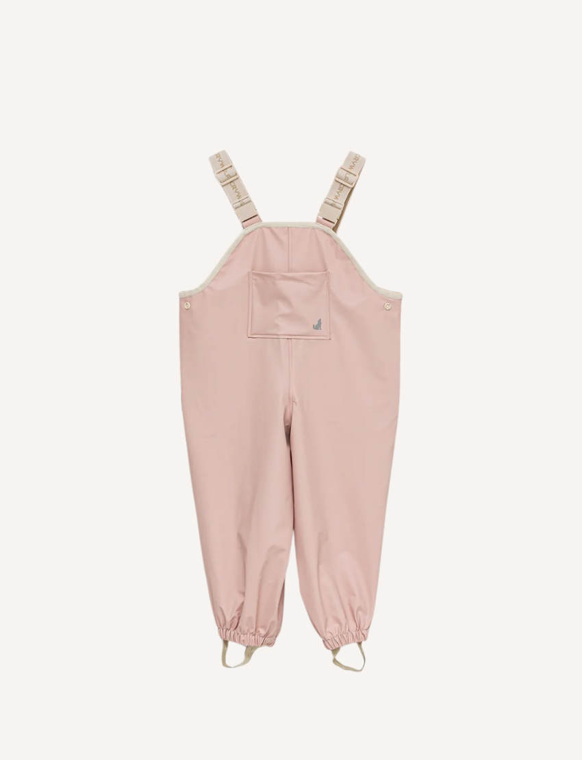 This image shows the back view of the Cry Wolf Rain Overalls in Dusty Pink, designed for children aged 3 years. The overalls feature elasticated cuffs at the ankles and adjustable shoulder straps with the brand's name printed on them. The words "A CRY WOLF" are printed across the back.