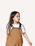 A pair of children's tan waterproof Rain Overalls from Cry Wolf with elasticated ankle cuffs, black adjustable shoulder straps, and the words 