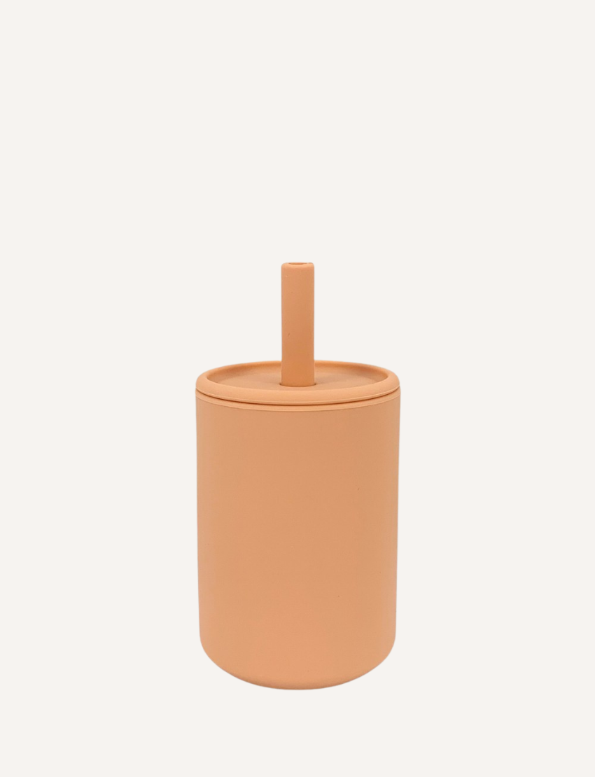 The Sippy Cup by Rommer Co is a light green, cylindrical container made of premium silicone, featuring a matching lid with a vertical handle on top. The smooth, matte material ensures it’s easy to clean. The product is showcased against a white background.