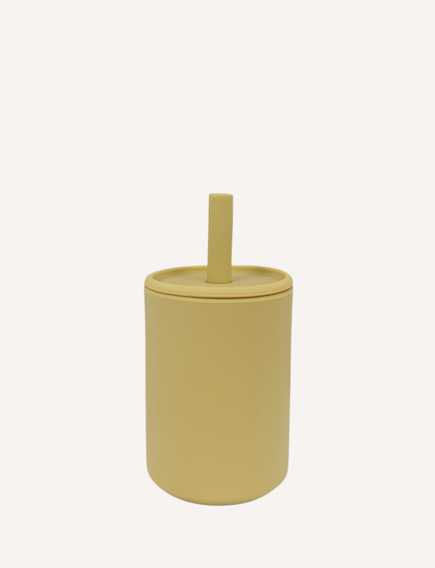 The Sippy Cup by Rommer Co is a light green, cylindrical container made of premium silicone, featuring a matching lid with a vertical handle on top. The smooth, matte material ensures it’s easy to clean. The product is showcased against a white background.